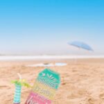 placard and a drink on beach sand